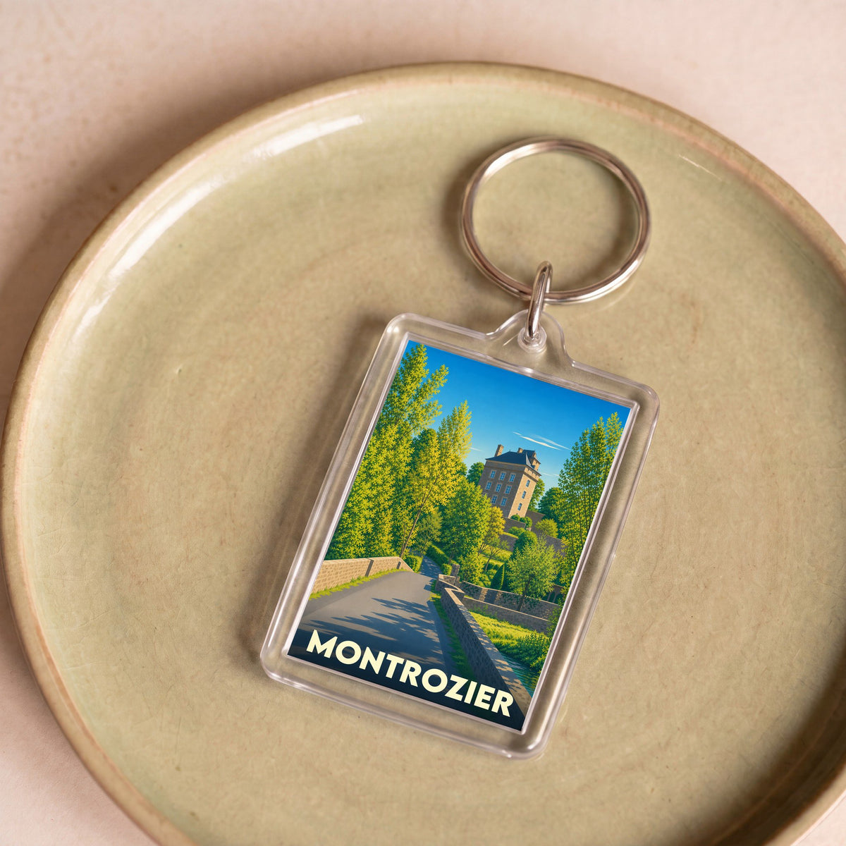 Porte-clés souvenir de la ville de Montrozier avec une illustration stylisée d'un paysage local.