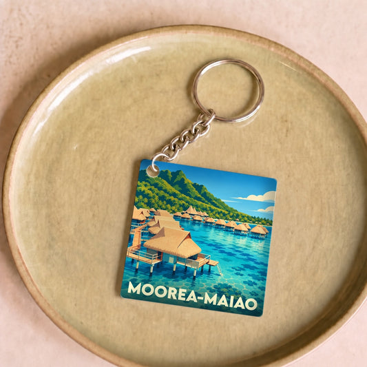 Porte-clés souvenir de Moorea-Maiao avec une illustration stylisée de bungalows sur pilotis.