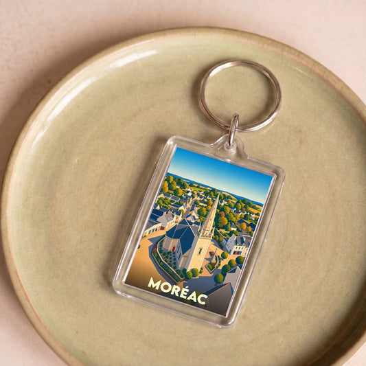Porte-clés souvenir de la ville de Moréac avec une illustration stylisée montrant l'église et les maisons.