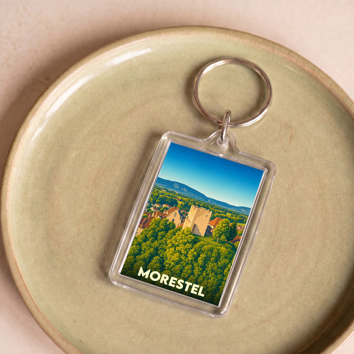 Porte-clés souvenir de la ville de Morestel avec une illustration stylisée de ses paysages et monuments.