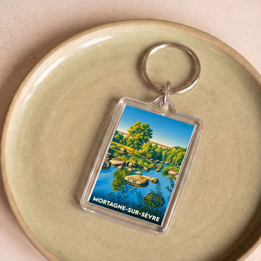 Porte-clés souvenir de la ville de Mortagne-sur-Sèvre avec une illustration stylisée d'un paysage de rivière.