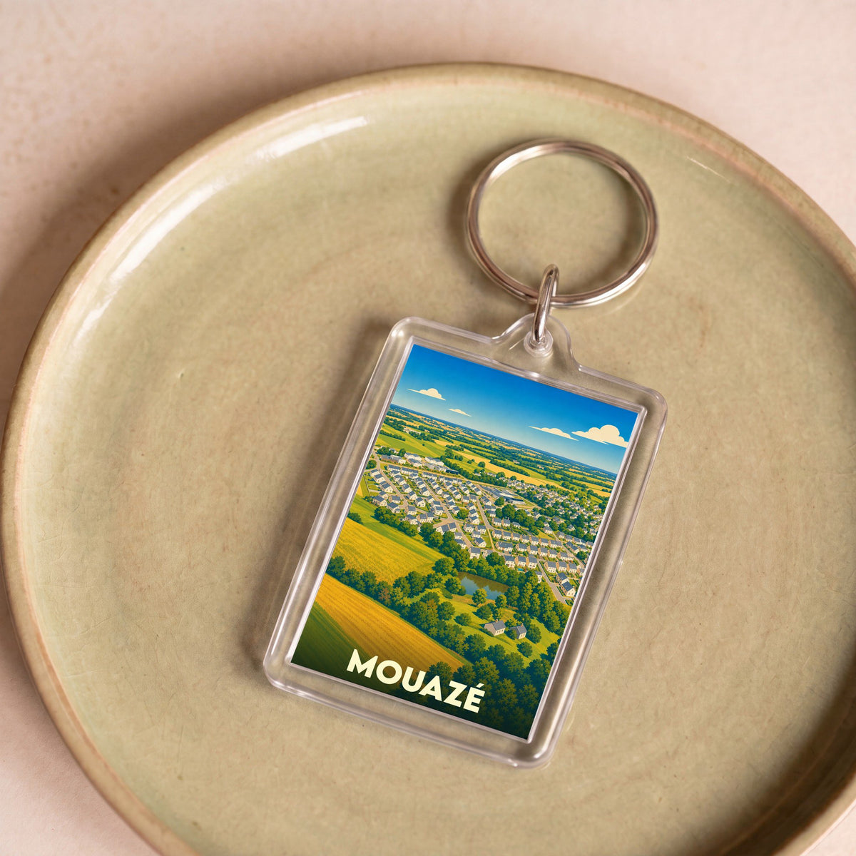 Porte-clés souvenir de la ville de Mouazé avec une illustration aérienne stylisée.
