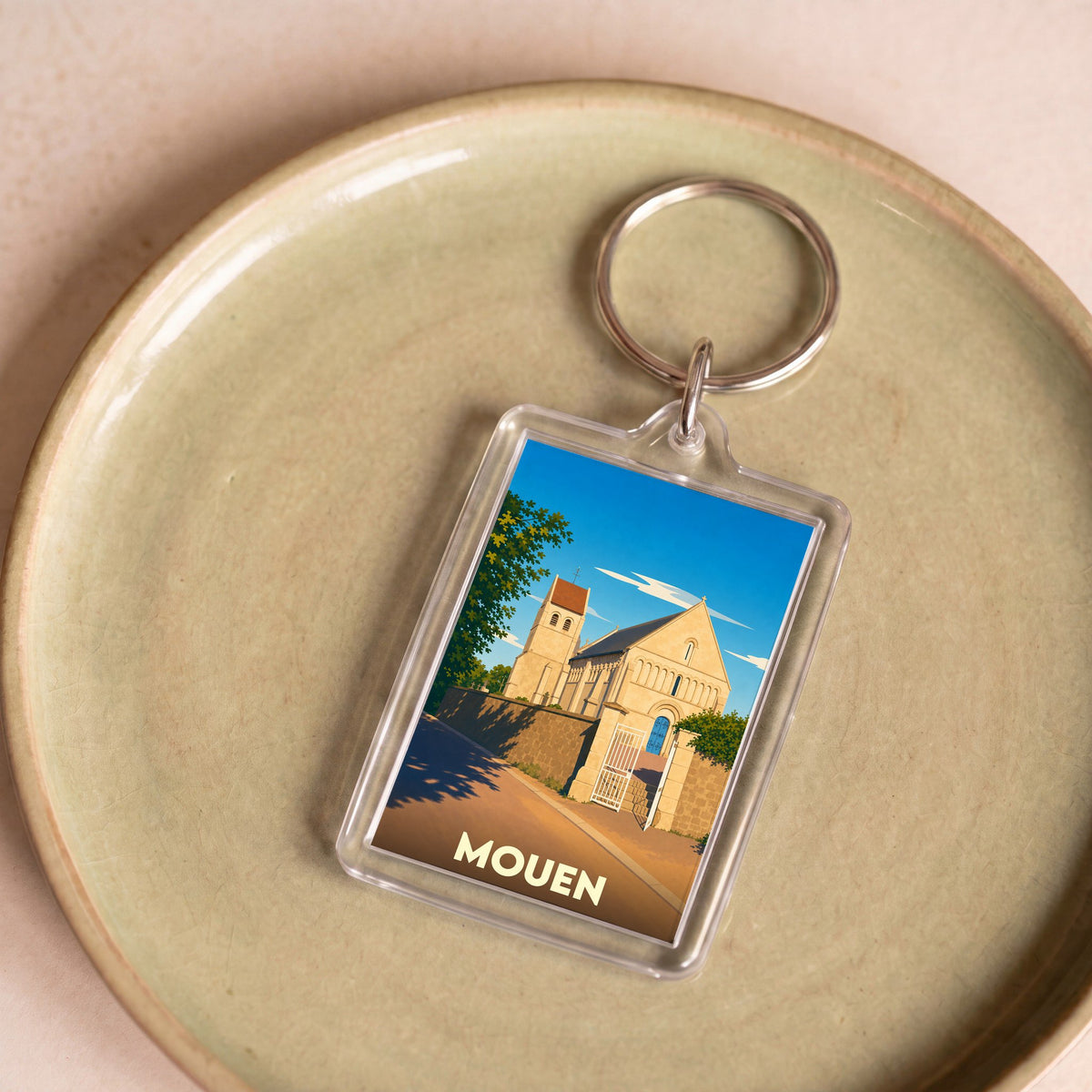 Porte-clés souvenir de la ville de Mouen avec une illustration stylisée de son église.