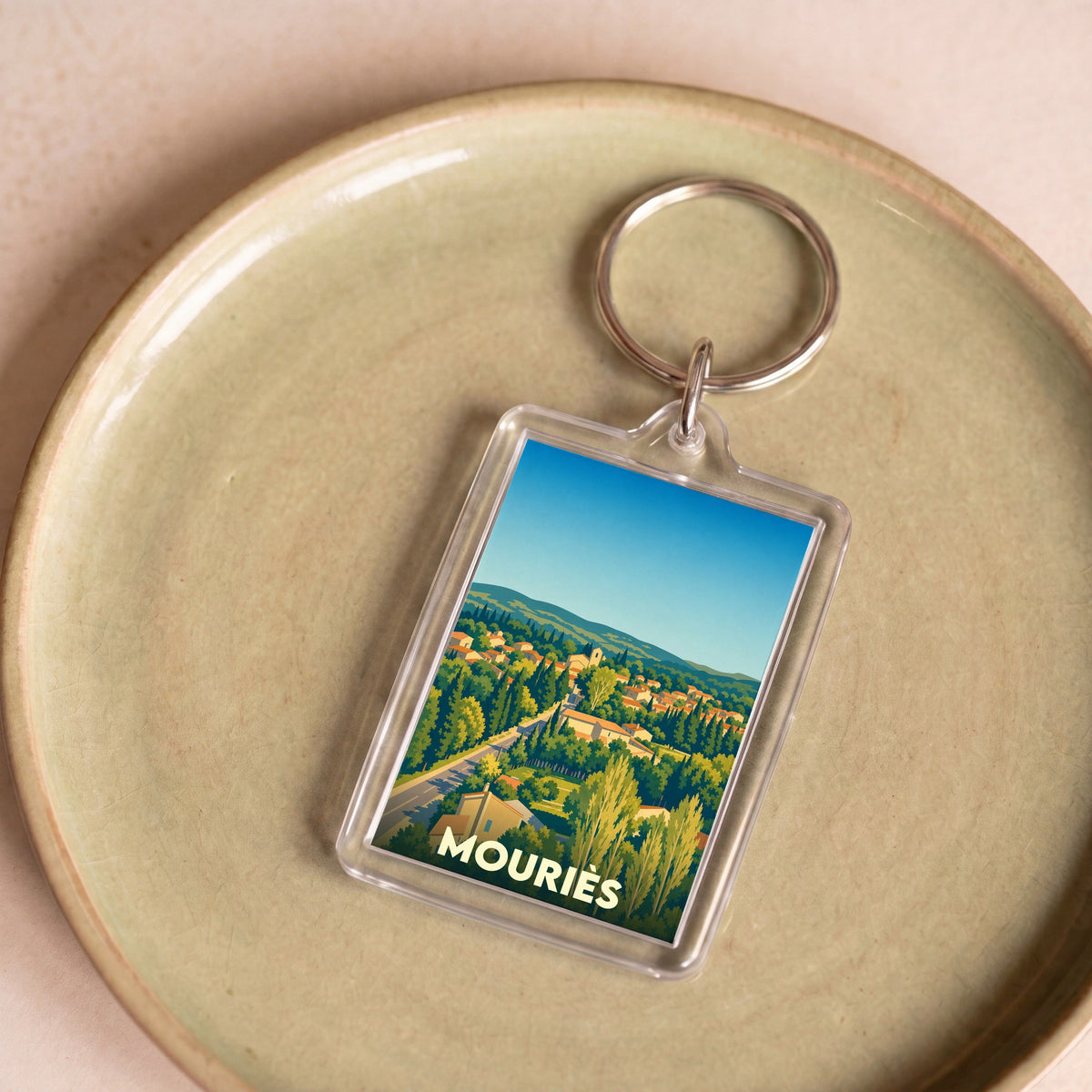Porte-clés souvenir de la ville de Mouriès avec une illustration stylisée.