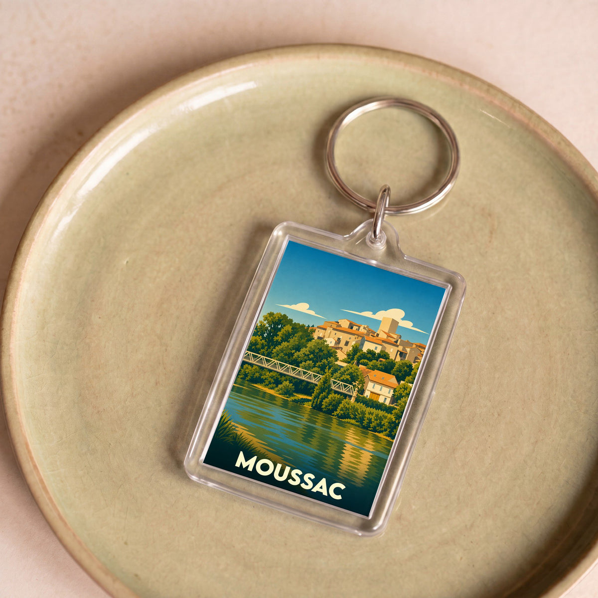 Porte-clés souvenir de la ville de Moussac avec une illustration stylisée.