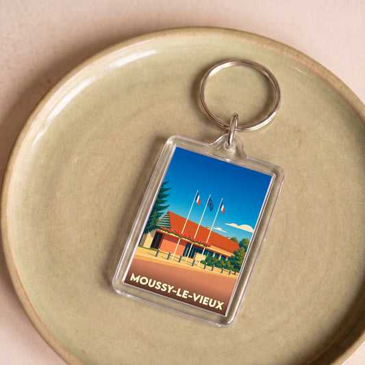 Porte-clés souvenir de la ville de Moussy-le-Vieux avec une illustration stylisée.