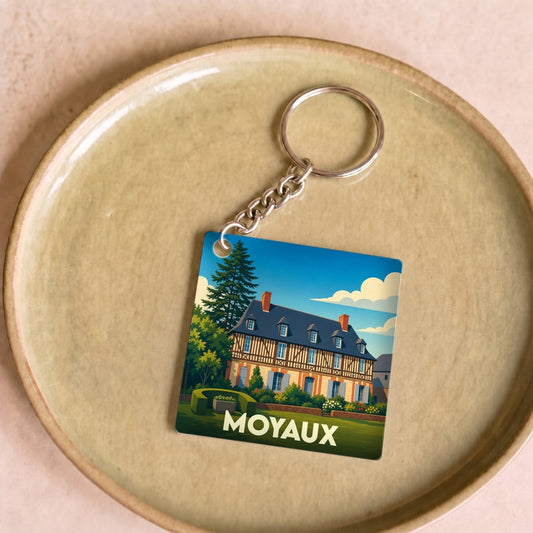 Porte-clés souvenir de la ville de Moyaux avec une illustration stylisée d'un manoir normand.