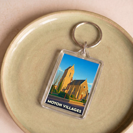 Porte-clés souvenir de la commune de Moyon Villages avec une illustration stylisée de son église.
