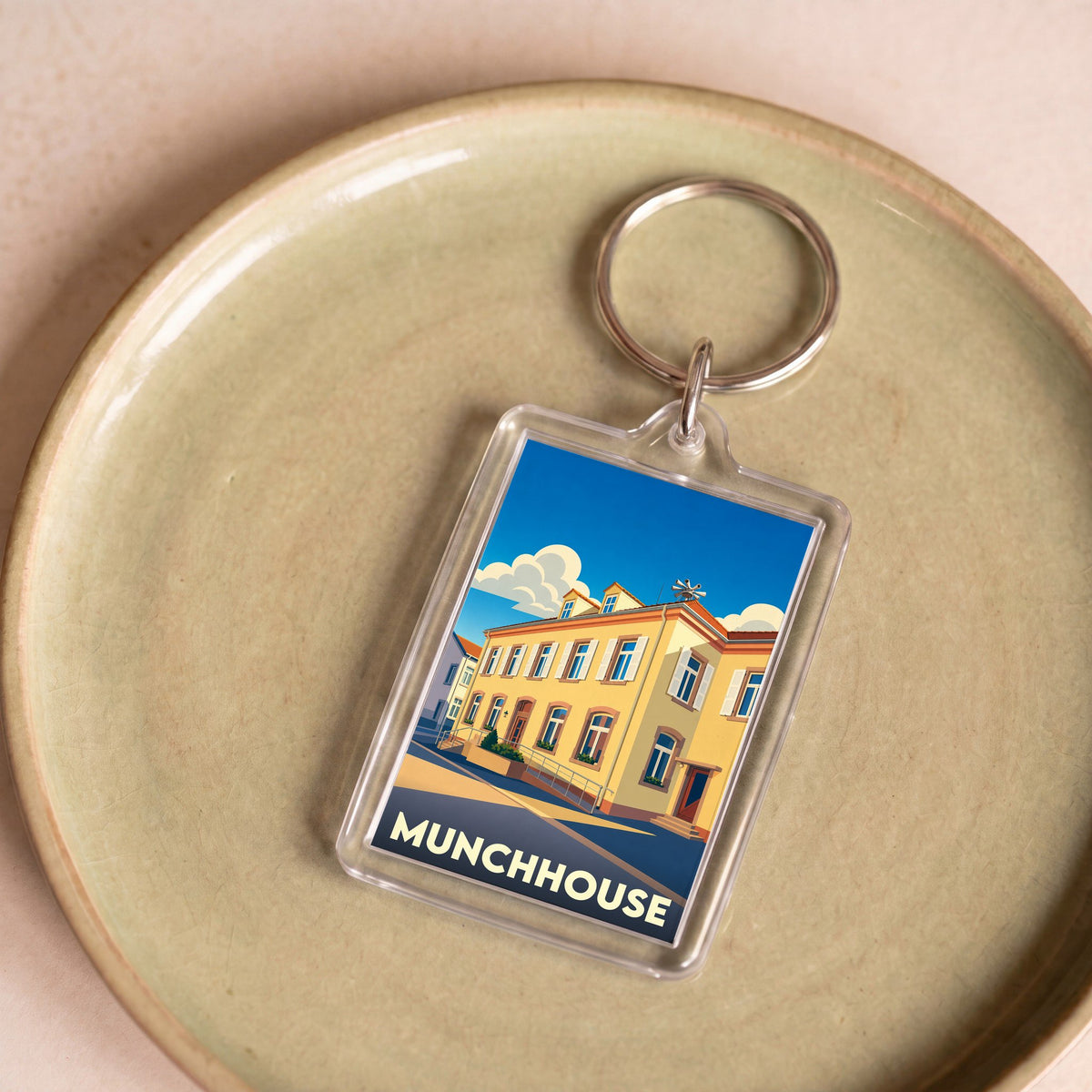 Porte-clés souvenir de la ville de Munchhouse avec une illustration stylisée d'un bâtiment coloré.