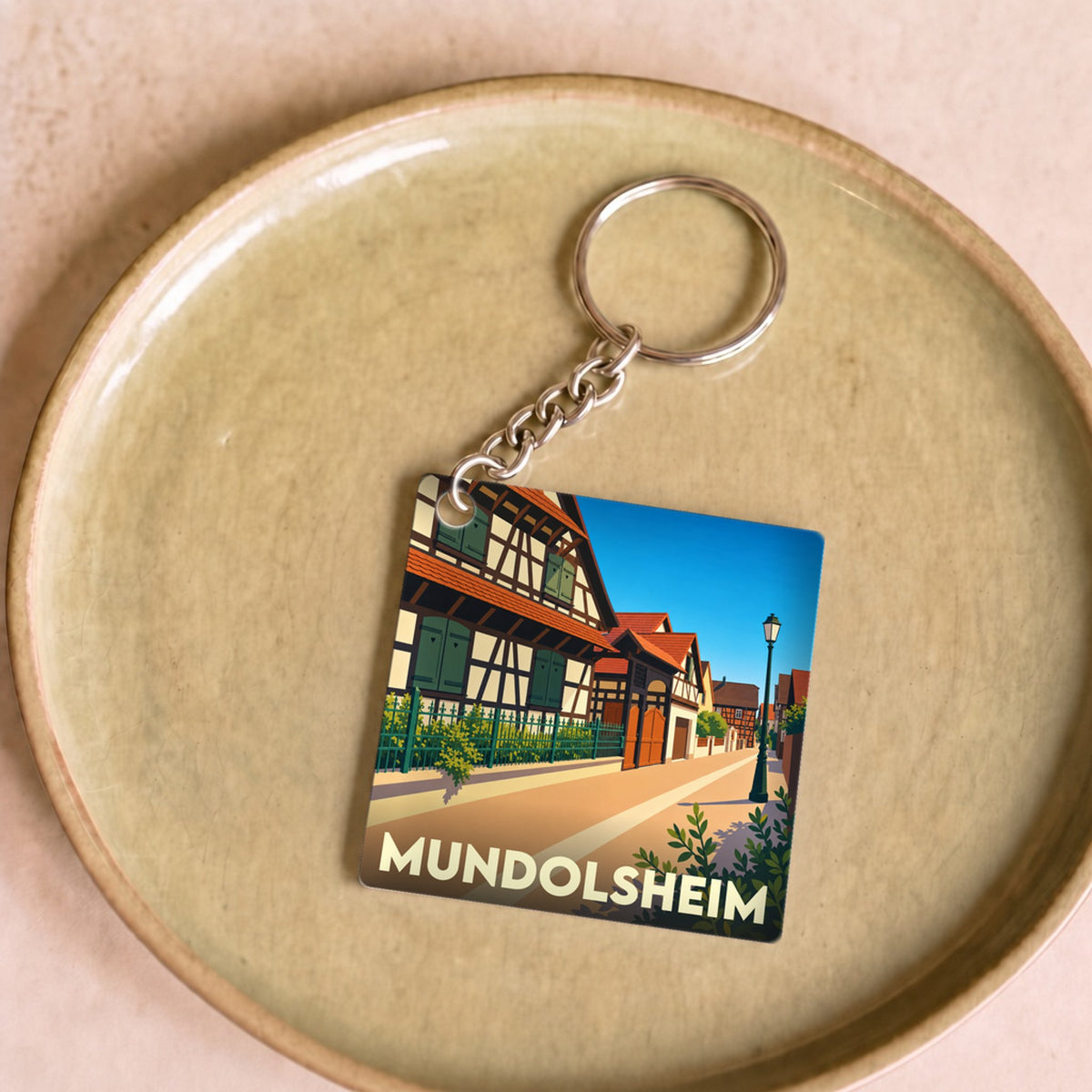 Porte-clés souvenir de la ville de Mundolsheim avec une illustration stylisée de maisons à colombages.