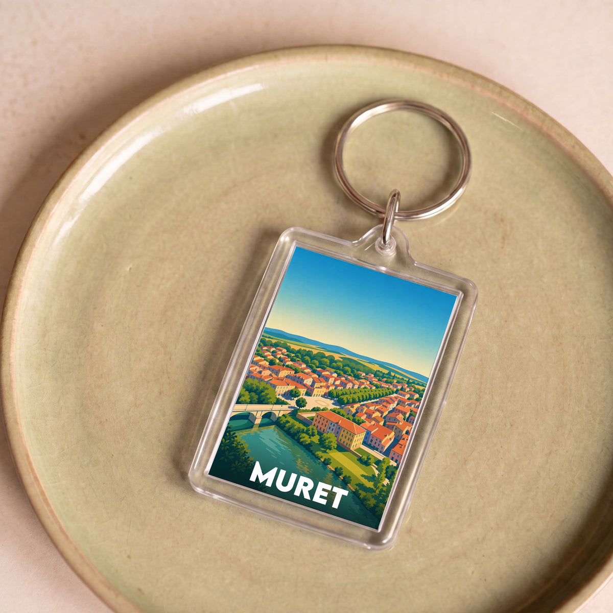 Porte-clés souvenir de la ville de Muret avec une illustration stylisée d'un paysage urbain.
