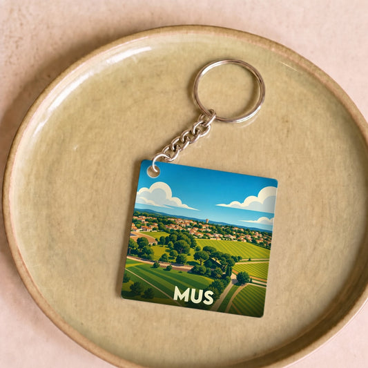 Porte-clés souvenir de la ville de Mus avec une illustration stylisée de son paysage.