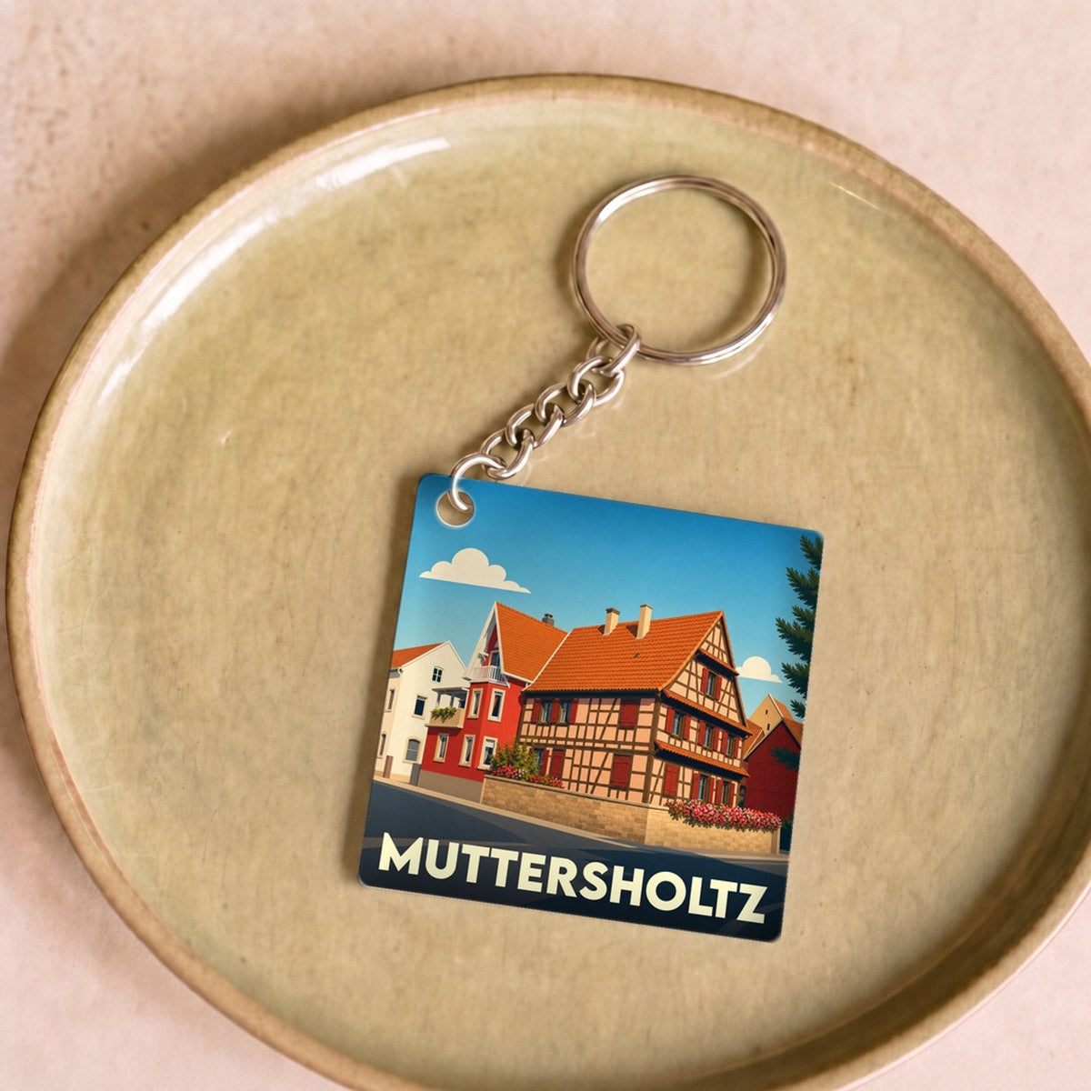 Porte-clés souvenir de la ville de Muttersholtz avec une illustration stylisée de maisons à colombages.