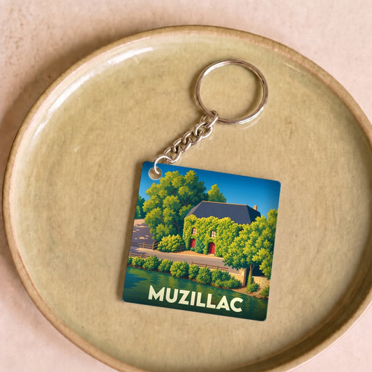 Porte-clés souvenir de la ville de Muzillac avec une illustration stylisée d'une maison au bord de l'eau.