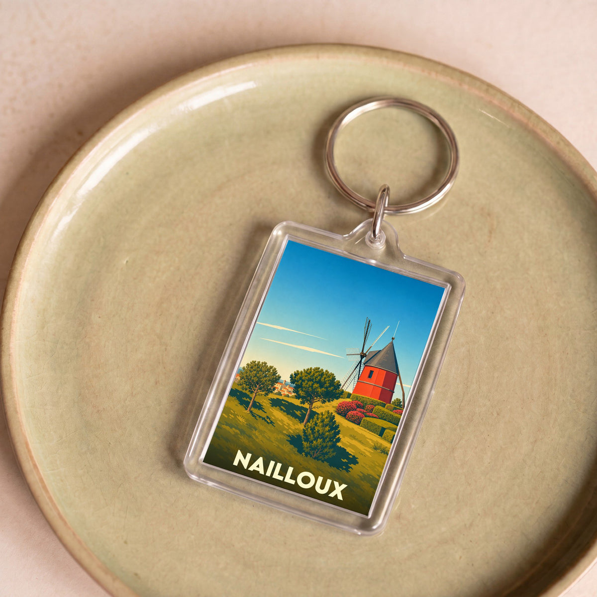 Porte-clés souvenir de la ville de Nailloux avec une illustration stylisée d'un moulin à vent rouge.