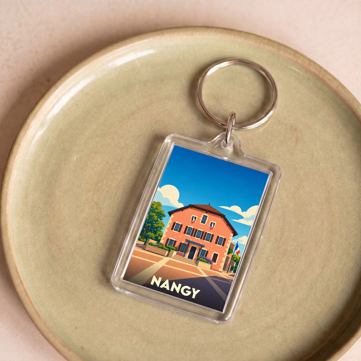 Porte-clés souvenir de la ville de Nangy avec une illustration stylisée d'un bâtiment traditionnel.