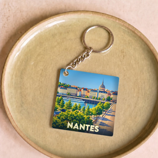 Porte-clés souvenir de la ville de Nantes avec une illustration stylisée d'un paysage urbain au bord de l'eau.