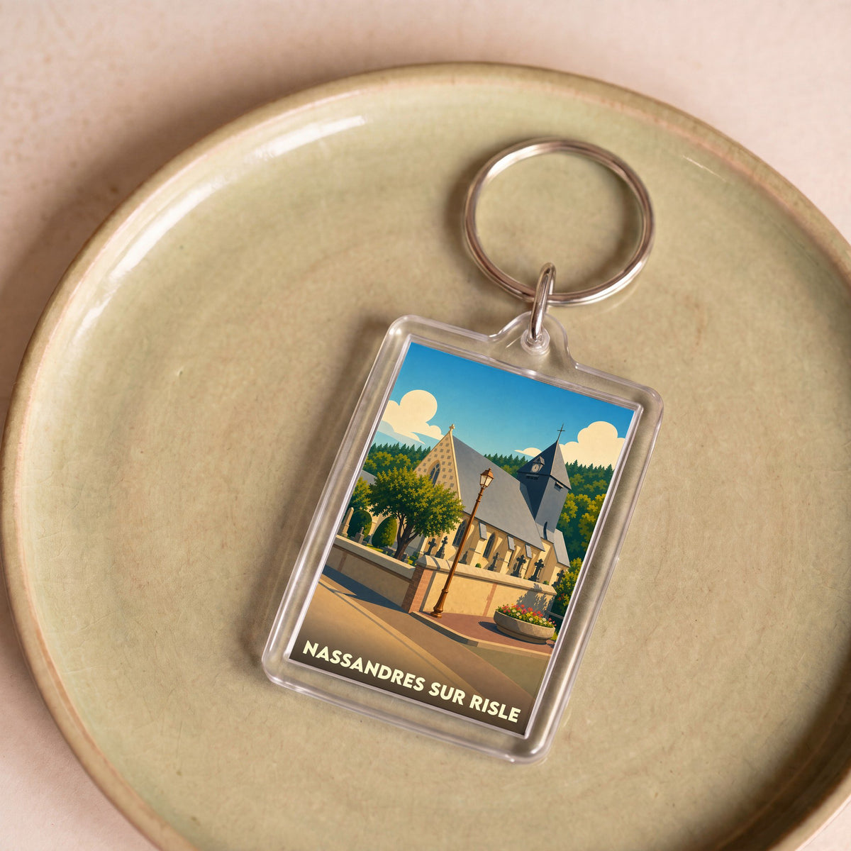 Porte-clés souvenir de la ville de Nassandres sur Risle avec une illustration stylisée de son église.