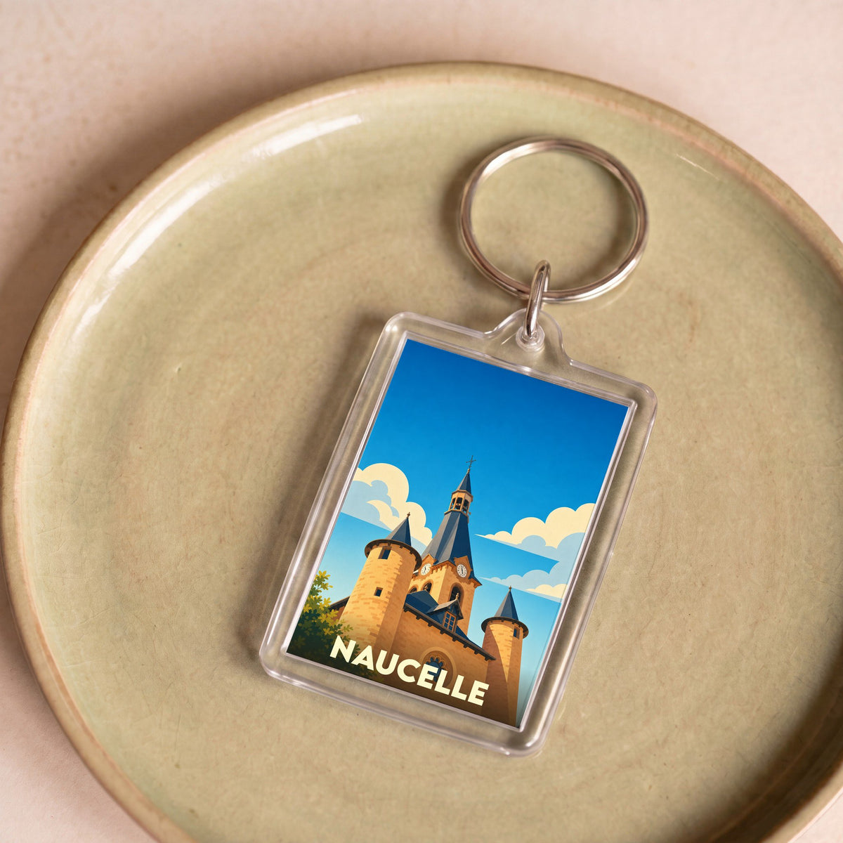 Porte-clés souvenir de la ville de Naucelle avec une illustration stylisée de son église.