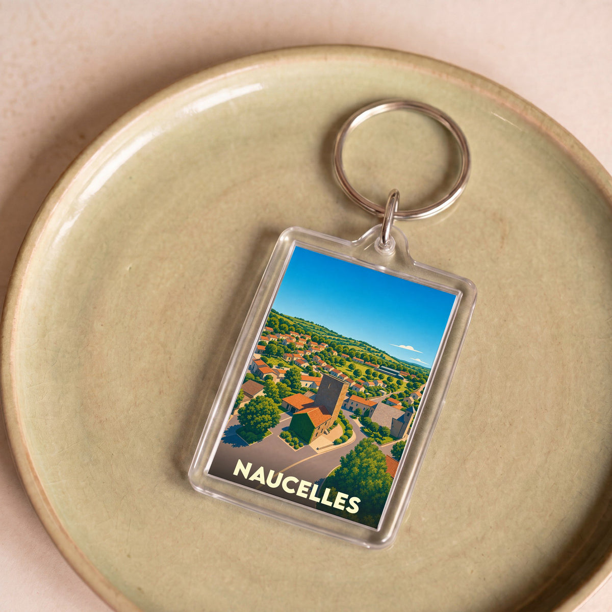 Porte-clés souvenir de la ville de Naucelles avec une illustration stylisée.