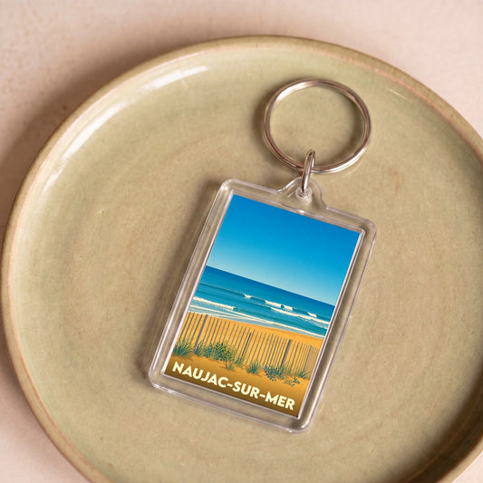 Porte-clés souvenir de Naujac-sur-Mer avec une illustration stylisée de sa plage.
