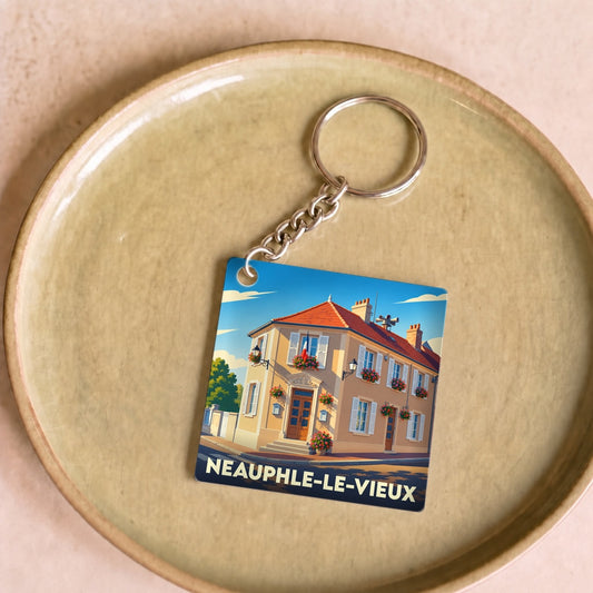 Porte-clés souvenir de la ville de Neauphle-le-Vieux avec une illustration stylisée d'un bâtiment fleuri.