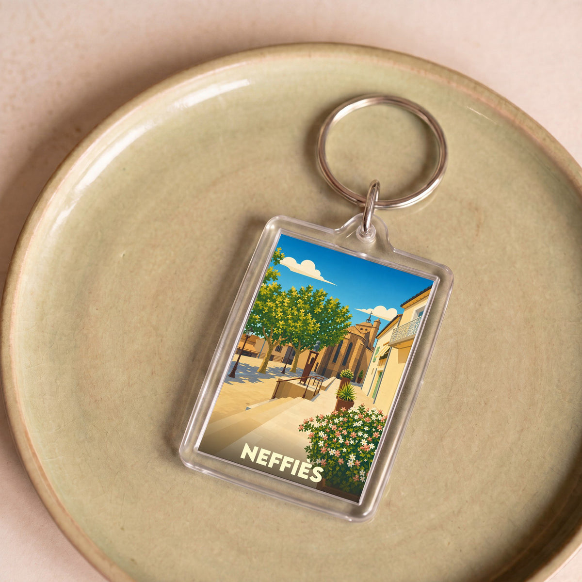 Porte-clés souvenir de la ville de Neffiès avec une illustration stylisée.