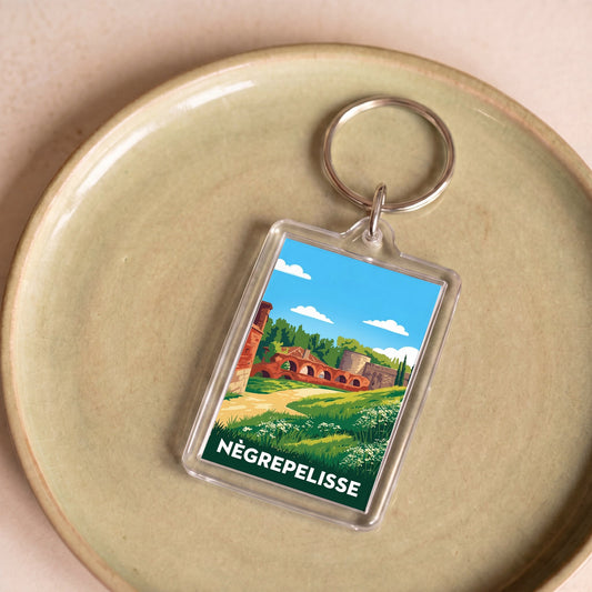 Porte-clés souvenir de la ville de Nègrepelisse avec une illustration stylisée d'un paysage local.