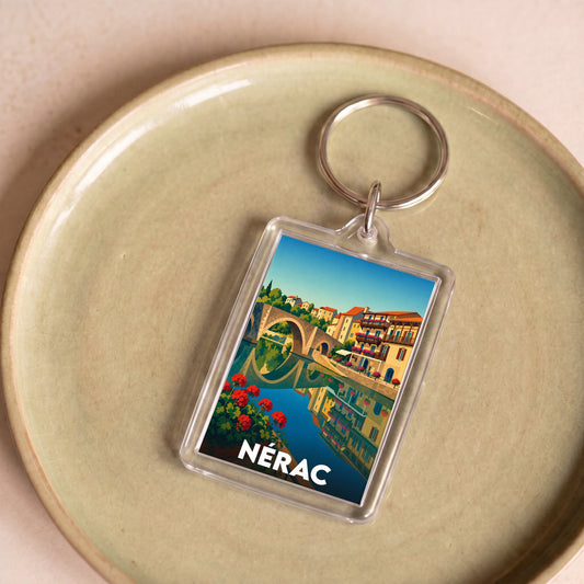 Porte-clés souvenir de la ville de Nérac avec une illustration colorée et stylisée de son pont emblématique.