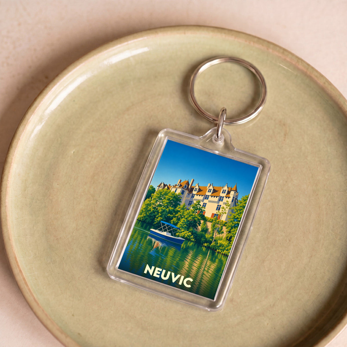 Porte-clés souvenir de la ville de Neuvic avec une illustration stylisée d'un château au bord de l'eau.