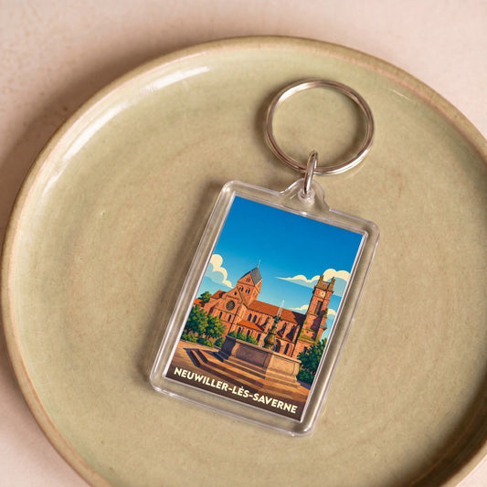 Porte-clés souvenir de la ville de Neuwiller-lès-Saverne avec une illustration stylisée de son église et d'une fontaine.