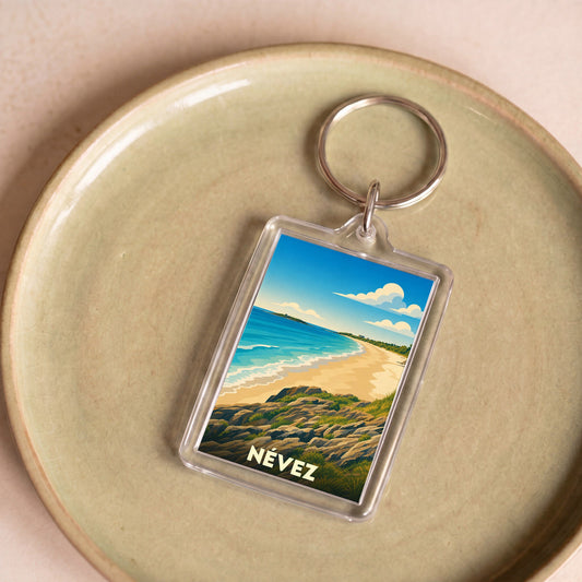 Porte-clés souvenir de la ville de Névez avec une illustration stylisée de sa plage et de sa côte rocheuse.