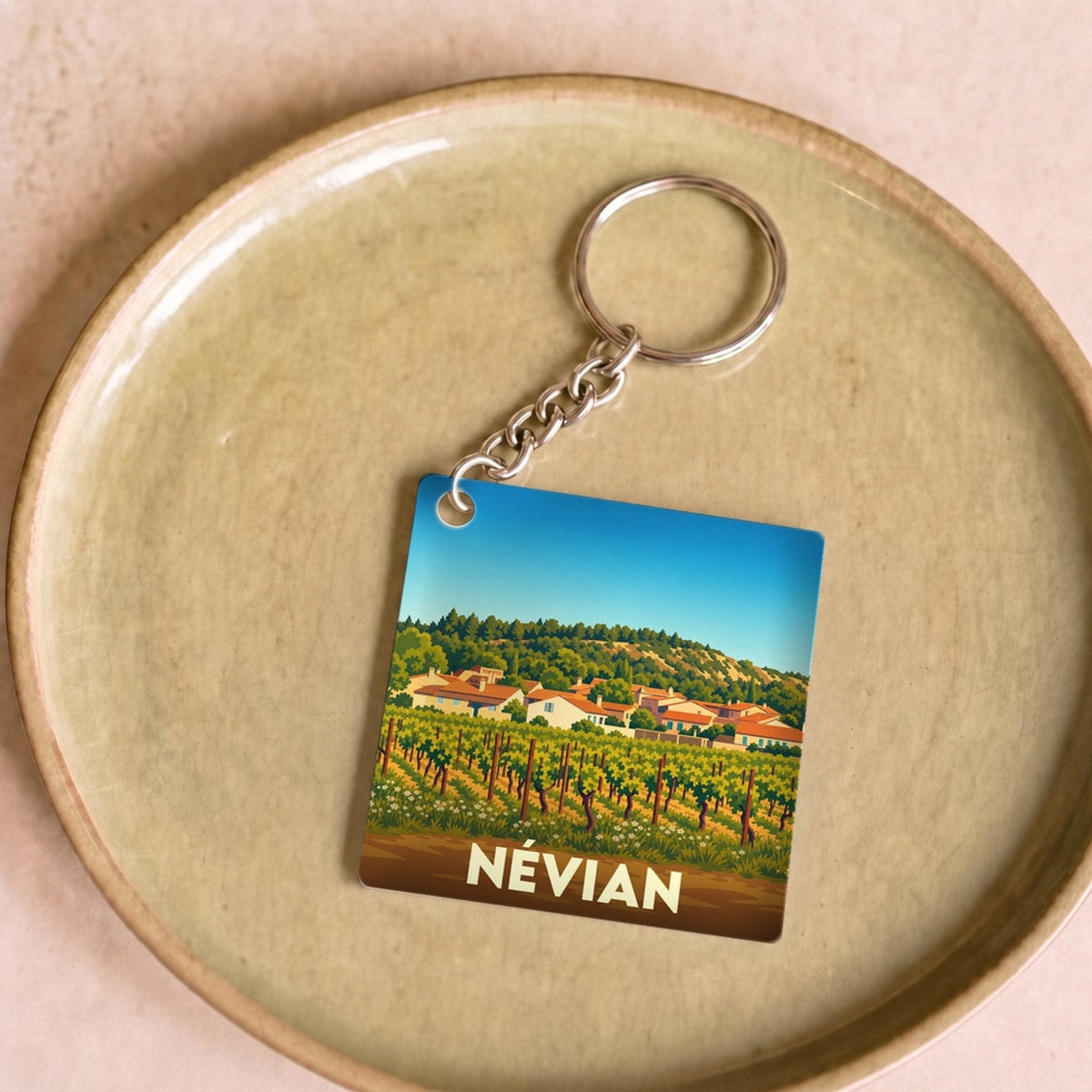 Porte-clés souvenir de la ville de Névian avec une illustration stylisée de son paysage.