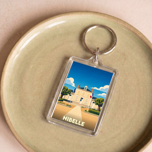 Porte-clés souvenir de la ville de Nibelle avec une illustration stylisée de sa mairie.