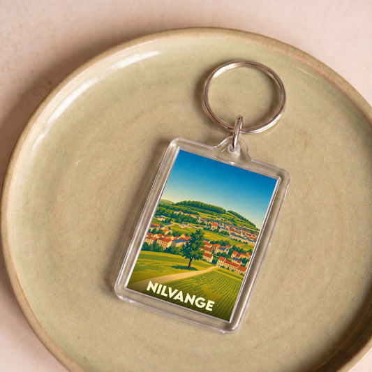 Porte-clés souvenir de la ville de Nilvange avec une illustration stylisée de son paysage urbain et rural.