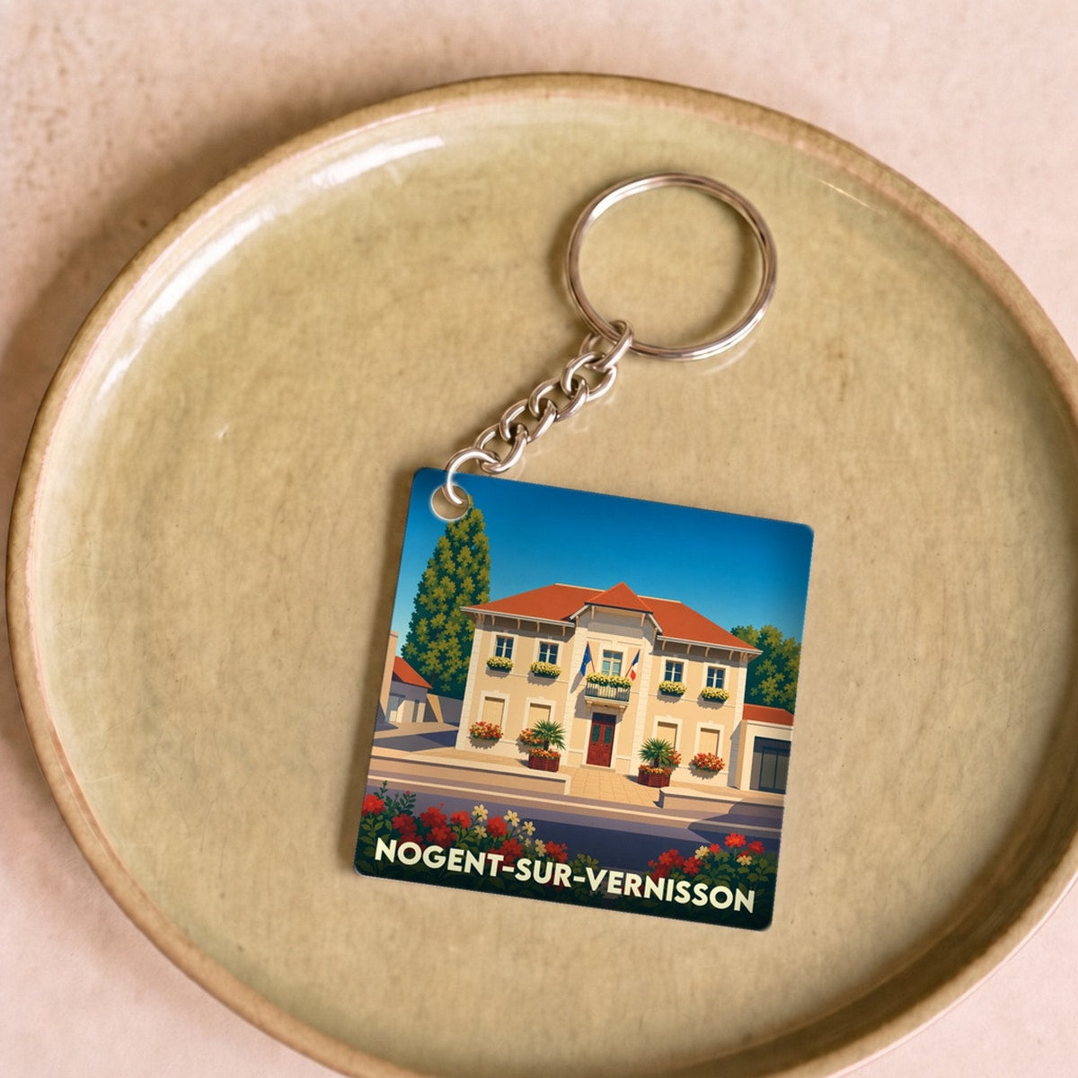 Porte-clés souvenir de la ville de Nogent-sur-Vernisson avec une illustration stylisée de sa mairie fleurie.