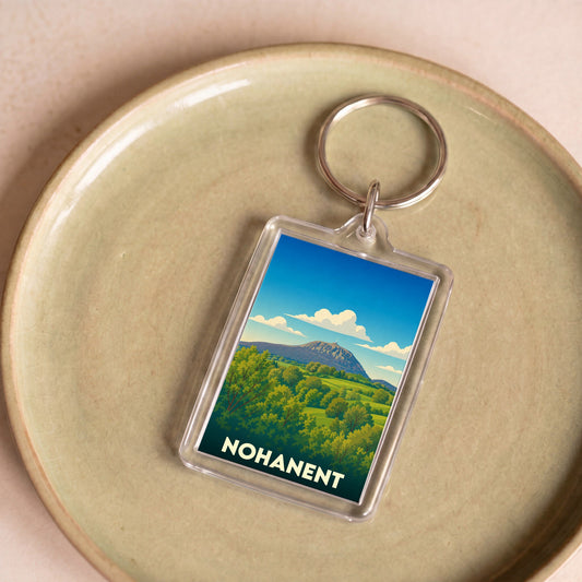 Porte-clés souvenir de la ville de Nohanent avec une illustration stylisée d'un paysage montagneux.
