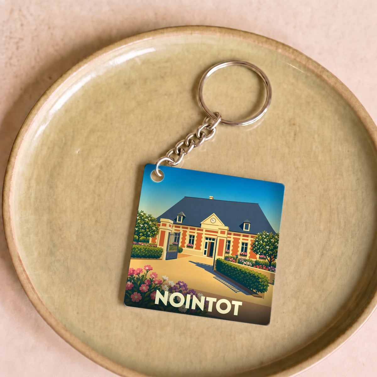 Porte-clés souvenir de la ville de Nointot avec une illustration stylisée de son patrimoine.