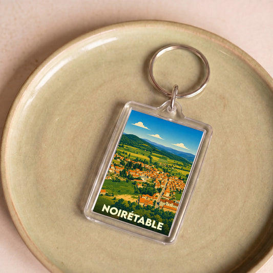 Porte-clés souvenir de la ville de Noirétable avec une illustration stylisée de son paysage urbain et naturel.