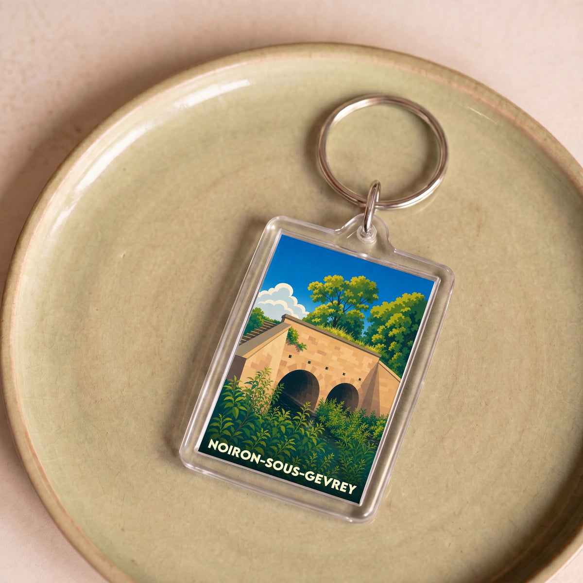 Porte-clés souvenir de Noiron-sous-Gevrey avec une illustration stylisée d'un pont en pierre.