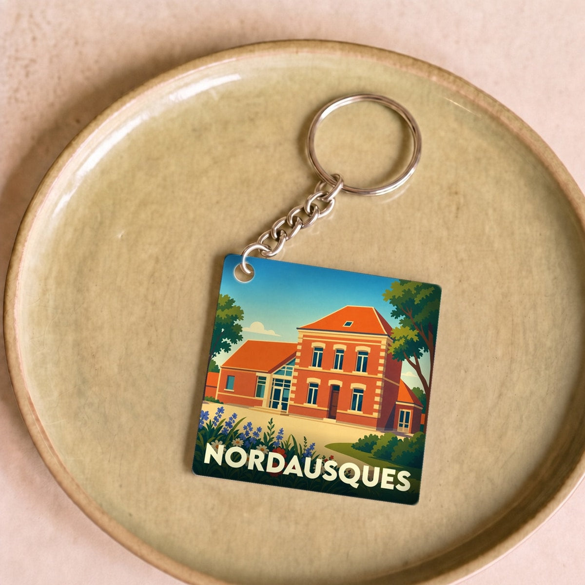 Porte-clés souvenir de la ville de Nordausques avec une illustration stylisée d'un bâtiment en briques.