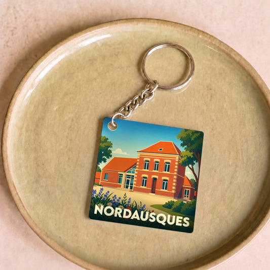 Porte-clés souvenir de la ville de Nordausques avec une illustration stylisée d'un bâtiment en briques.