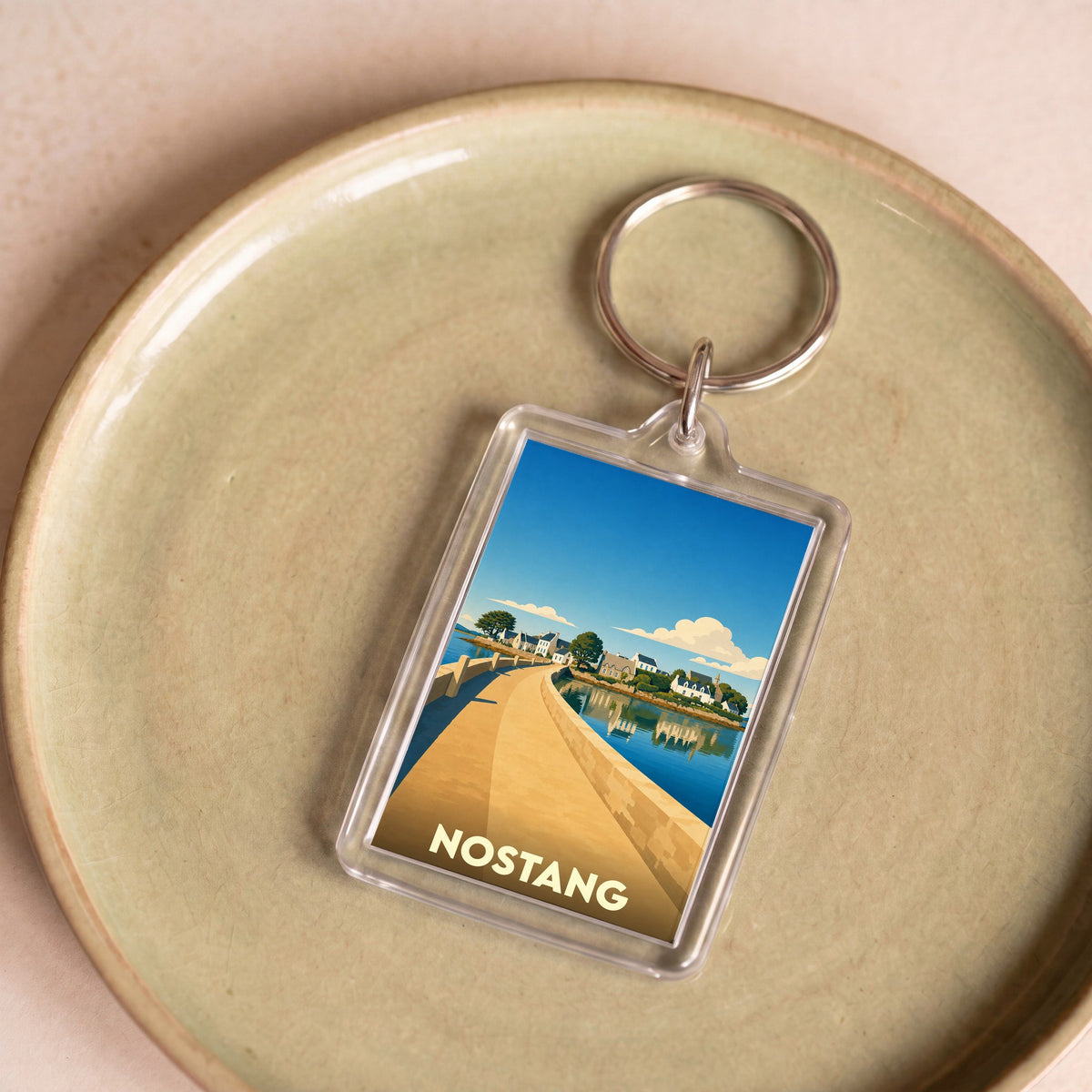 Porte-clés souvenir de la ville de Nostang avec une illustration stylisée de son front de mer.