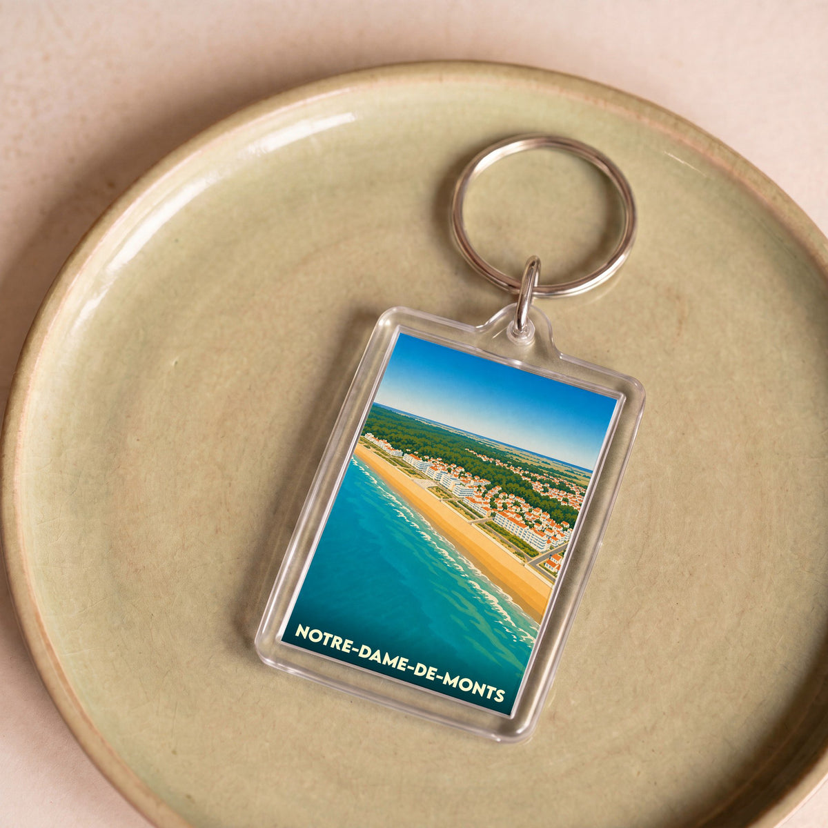 Porte-clés souvenir de la ville de Notre-Dame-de-Monts avec une illustration stylisée du littoral.
