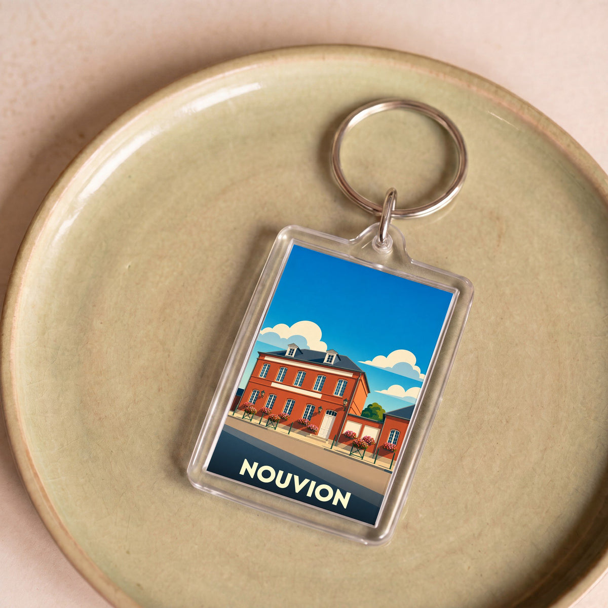 Porte-clés souvenir de la ville de Nouvion avec une illustration stylisée d'un bâtiment historique.