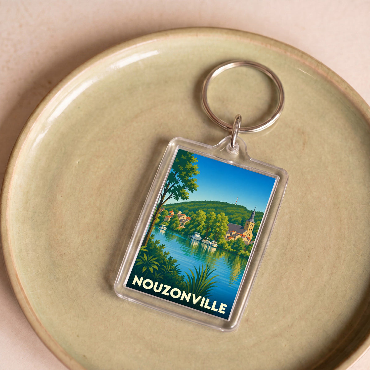 Porte-clés souvenir de la ville de Nouzonville avec une illustration stylisée des bords de Meuse.