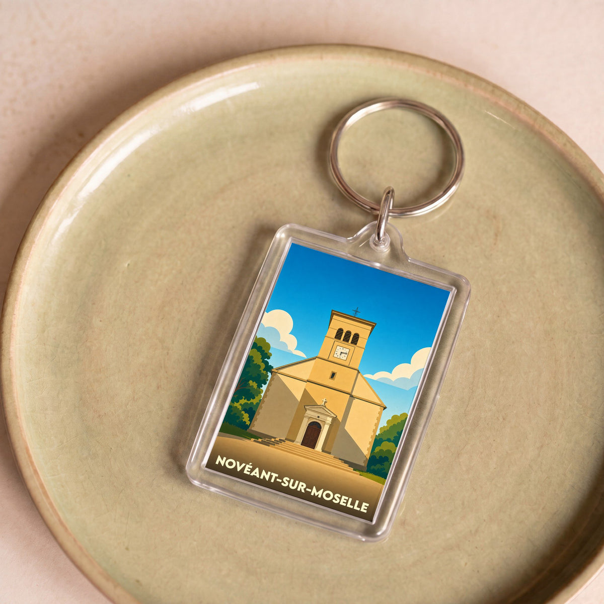 Porte-clés souvenir de la ville de Novéant-sur-Moselle avec une illustration stylisée de son église.