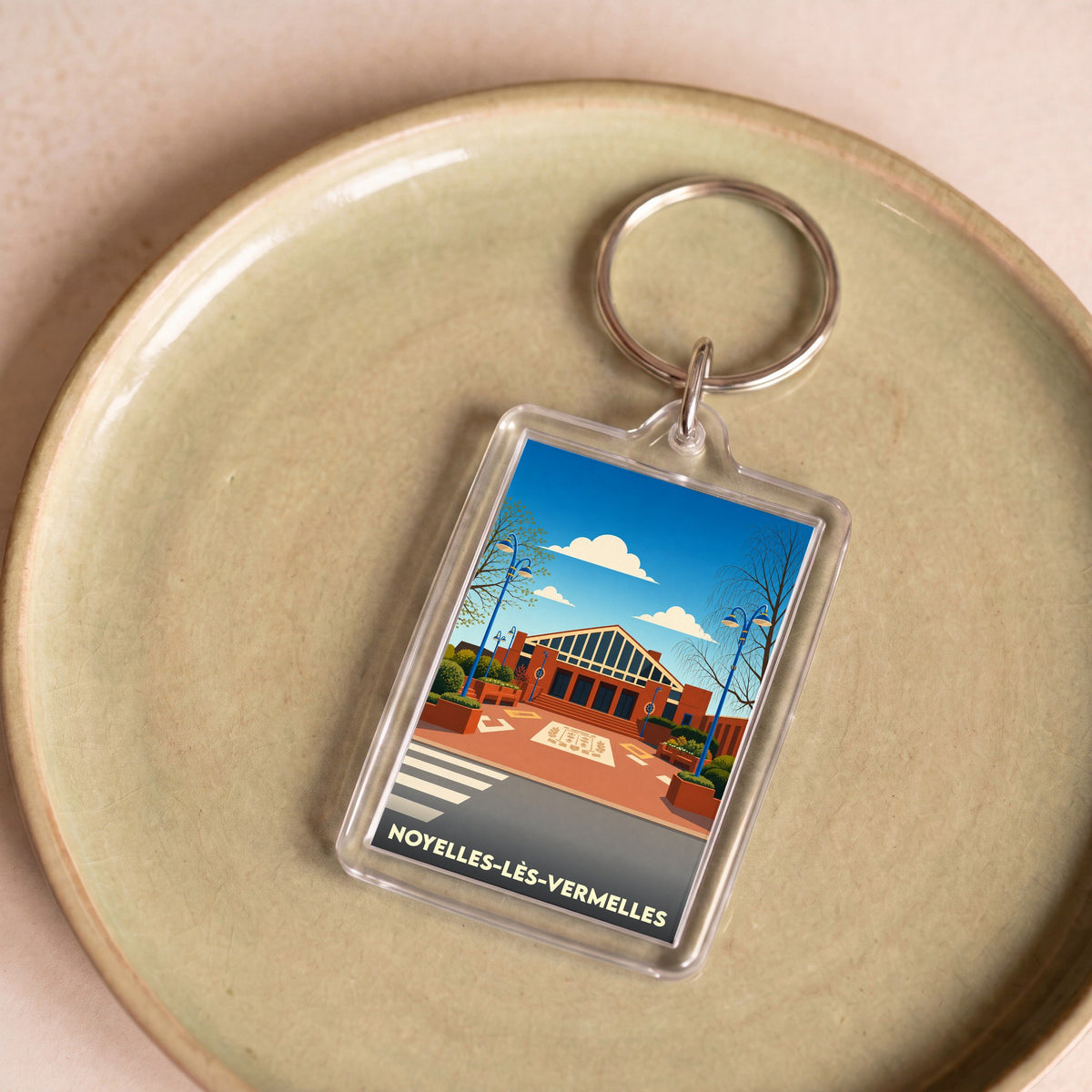 Porte-clés souvenir de la ville de Noyelles-lès-Vermelles avec une illustration stylisée.