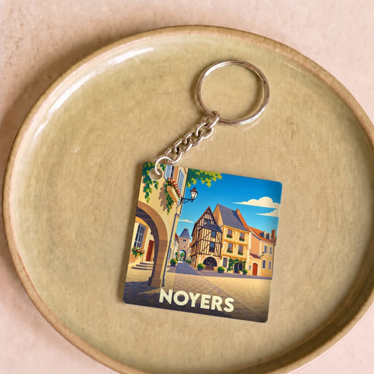 Porte-clés souvenir de la ville de Noyers avec une illustration stylisée de ses maisons à colombages.