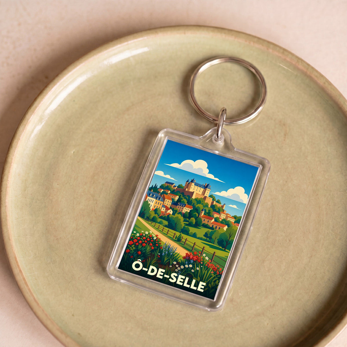 Porte-clés souvenir de la ville de Ô-de-Selle avec une illustration paysagère stylisée.
